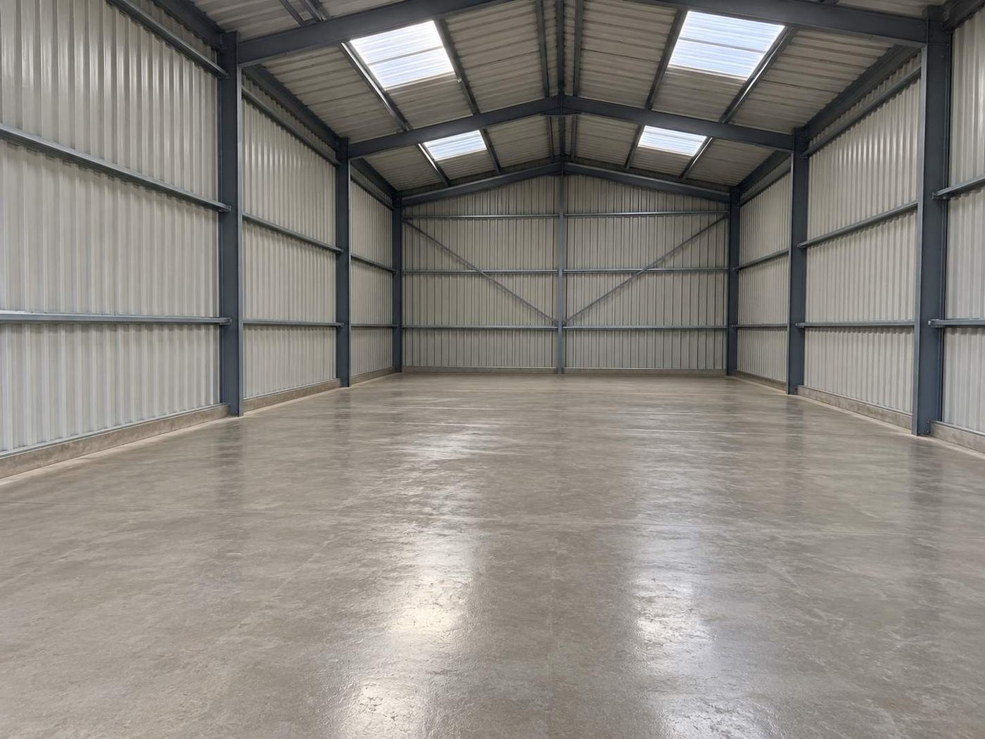 Inside a finished steel-framed commercial unit with a smooth concrete floor, insulated wall panels and rooflights