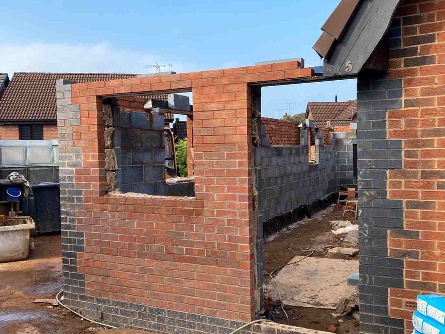 Brick extension shell with window and door openings under construction