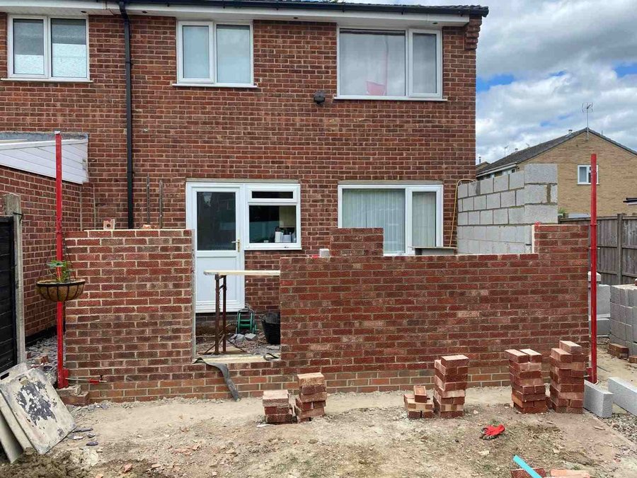 Rear extension brickwork under construction behind the original house