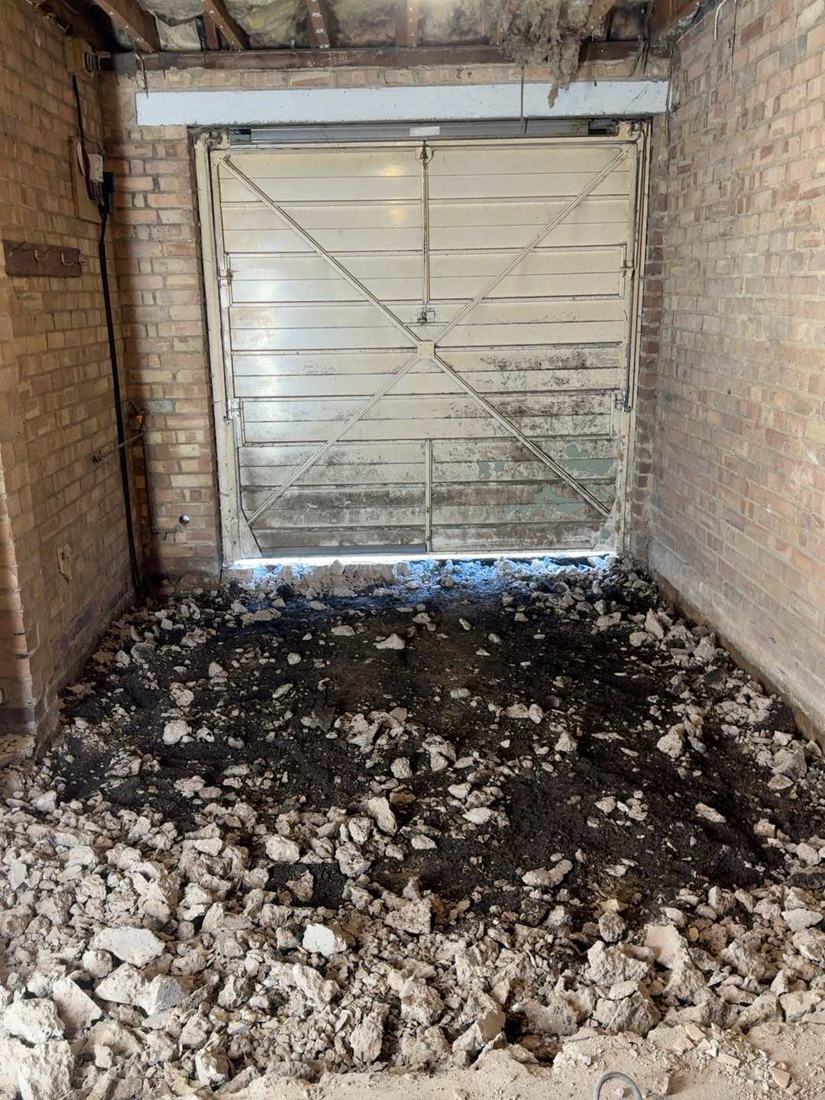 The same garage before the conversion: old up-and-over door and the concrete floor broken out ready for a new insulated floor