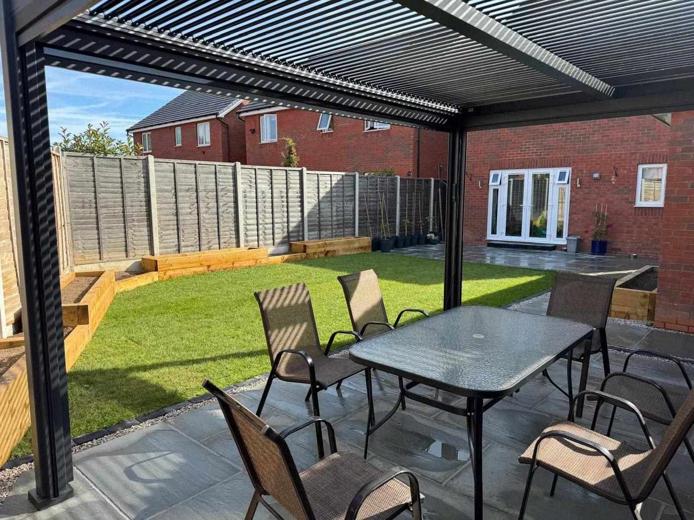 View from under the pergola across the new lawn, sleeper planters and sandstone patio back to the house in Meir, Stoke-on-Trent