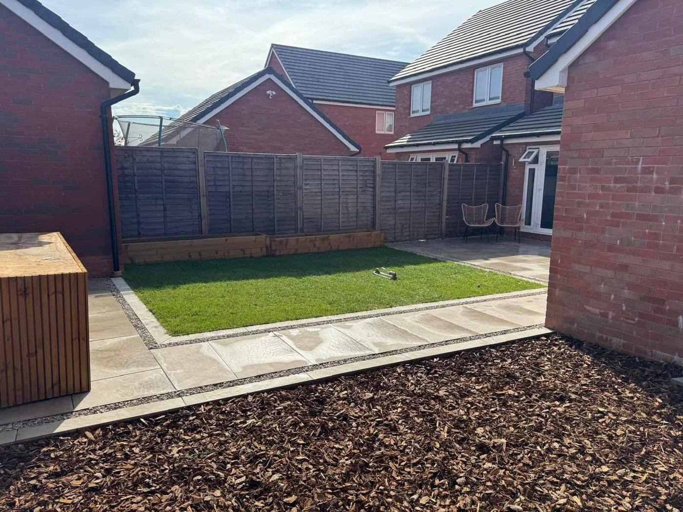 Finished family garden in Uttoxeter: beige porcelain path, new lawn, raised sleeper beds and a bark-chip play area