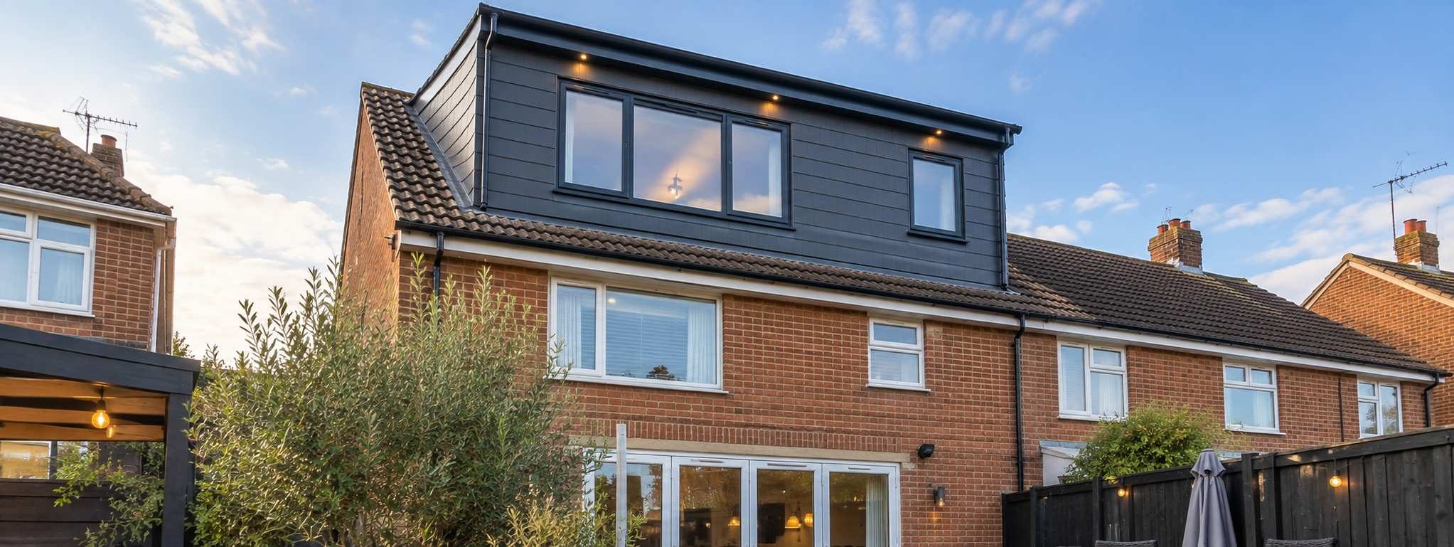 Rear dormer loft conversion with dark grey cladding and anthracite windows on a red-brick semi-detached house