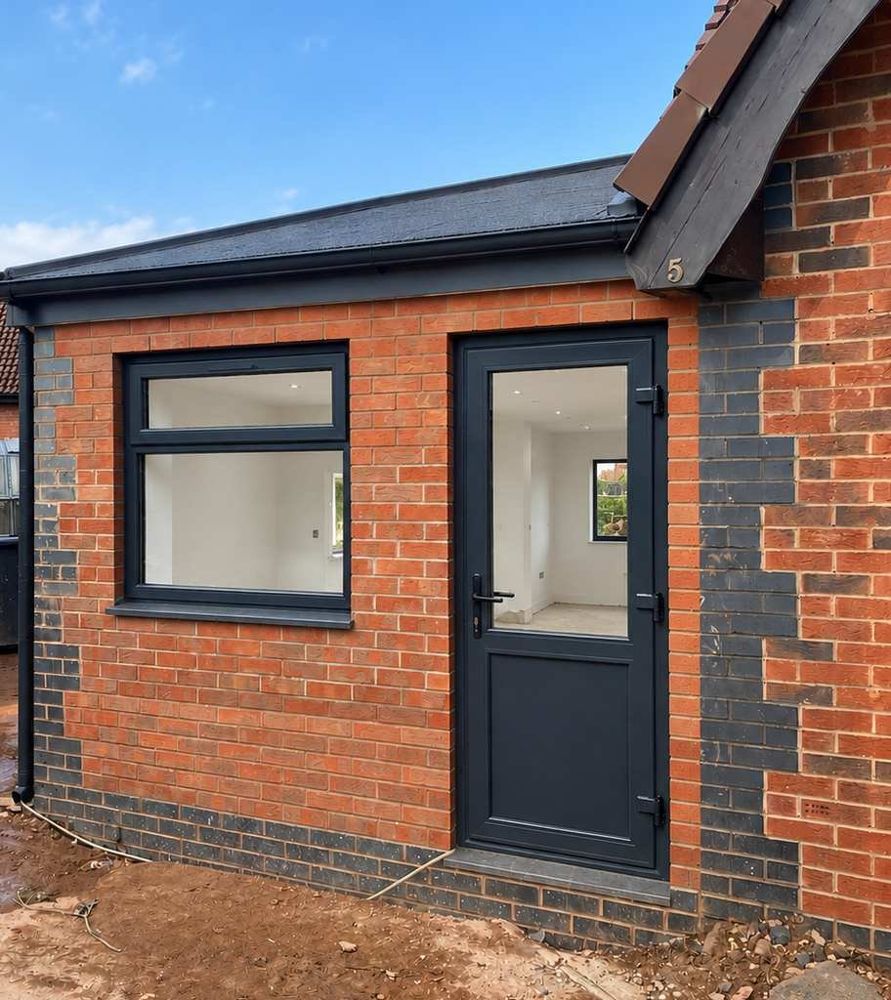 Completed side extension on a bungalow in Bedford, with an anthracite-grey window and door set into new red brickwork